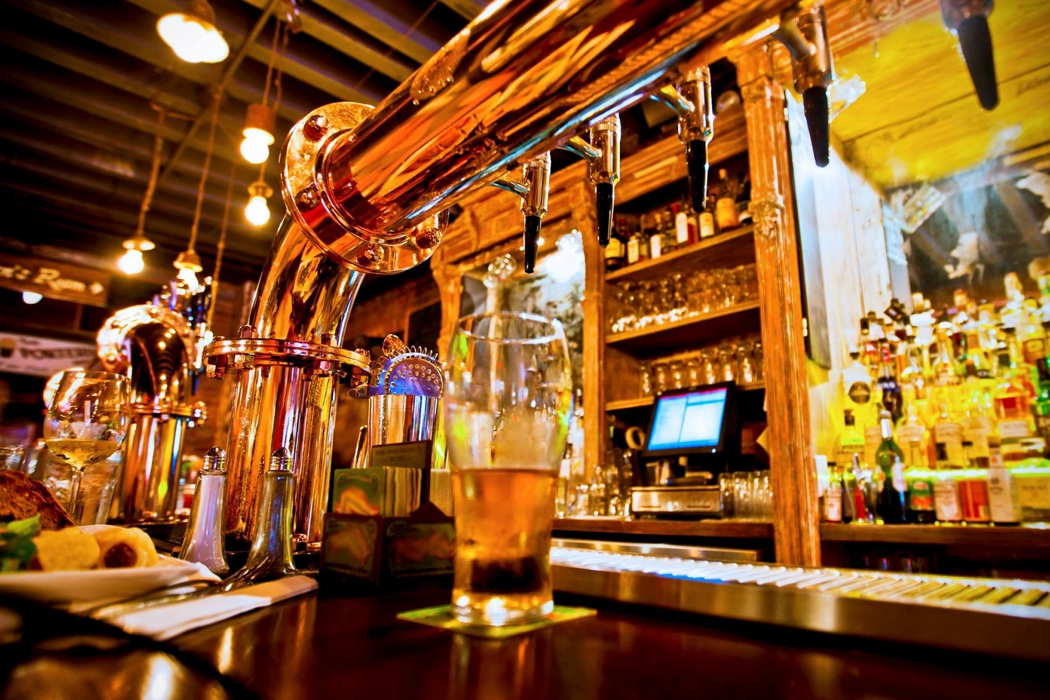 A glass of beer on a bar counter with a wooden tap system.