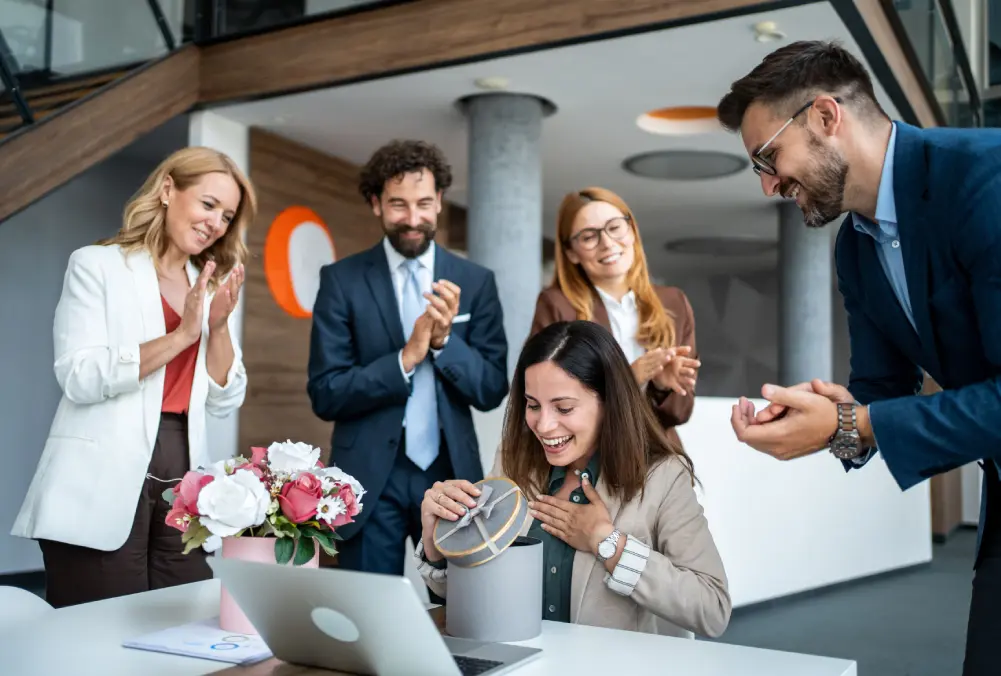 Colleagues celebrating a woman's work success in an office.
