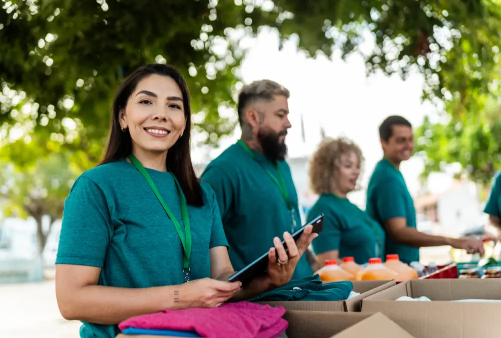 Volunteers packing food boxes outdoors, smiling and engaged.