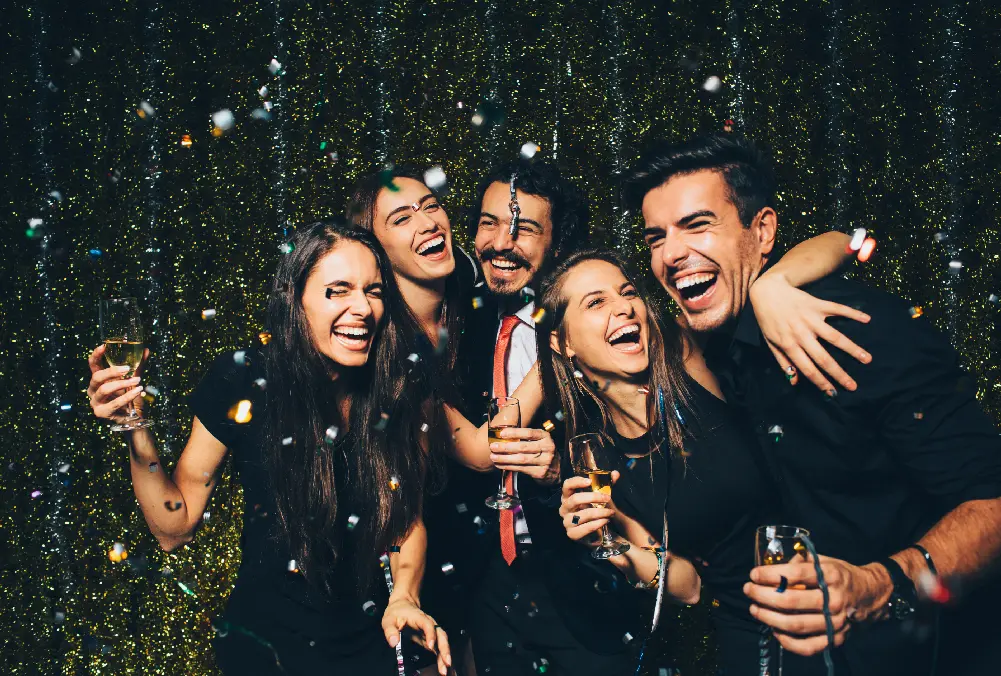 Group of friends celebrating joyfully with drinks in hand.