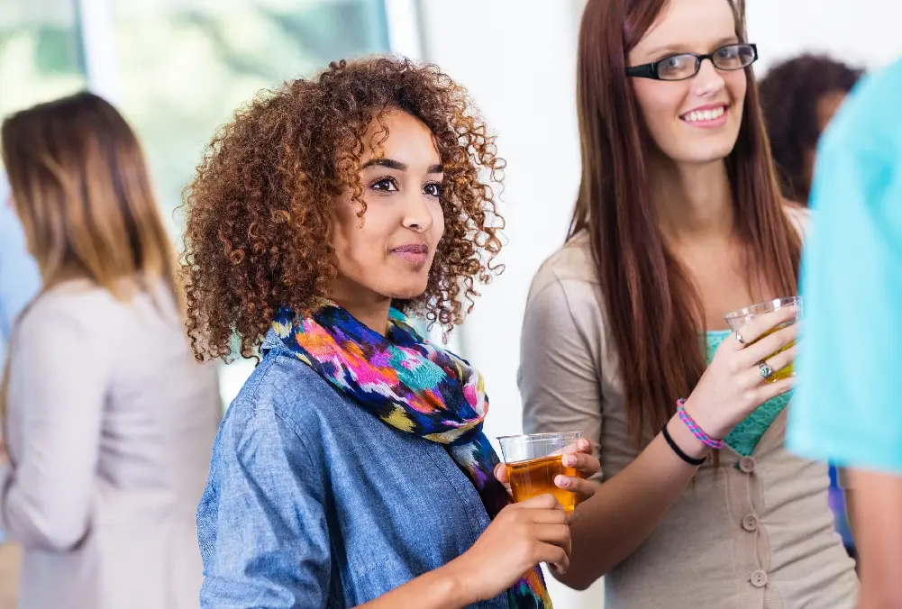 Two young women enjoying drinks at a social gathering.